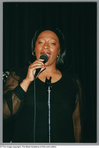 Portrait of Benita Arterberry singing into a microphone