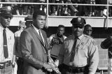 Muhammad Ali shaking hands with a policeman on the football field during homecoming activities for Alabama State College on Thanksgiving Day in Montgomery, Alabama.