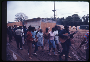 Guitarists leads a line of residents past a graffiti-covered wall in the Resurrection City encampment