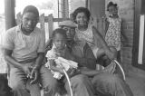 Jimmy Bates with children on the front porch of a brick house in Newtown, a neighborhood in Montgomery, Alabama.