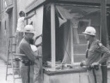 Police watch men boarding up storefront after riot, Rochester, NY, 1964