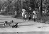 Women and children walking down a dirt road in Newtown, a neighborhood in Montgomery, Alabama.