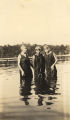 Three young African American women standing in knee-deep water.