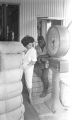 Woman and young man weighing a bale of cotton on a large scale at a cotton gin near Mount Meigs in Montgomery County, Alabama.