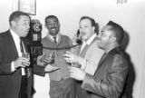 Roscoe Williams, Bobby Moore, and two other men standing around a pay telephone at the Laicos Club in Montgomery, Alabama.