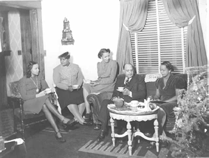 Man and women seated in living room drinking coffee.