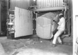 Man removing a bale of cotton from a baler in a gin near Mount Meigs in Montgomery County, Alabama.