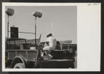 A young radio engineer resident of Tule Lake, formerly of the Hollywood Sound Institute, plays records on the public address system on the arrival or departure of each segregation train. Photographer: Mace, Charles E
