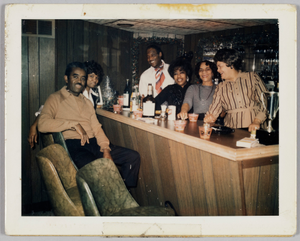 Photographic print of a group of people gathered around a bar