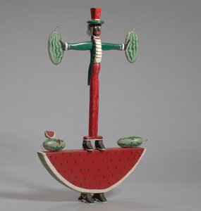 Sculpture in the form of a caricatured man standing on a watermelon slice