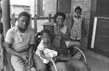 Jimmy Bates with children on the front porch of a brick house in Newtown, a neighborhood in Montgomery, Alabama.