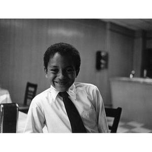 Young boy wearing a necktie and smiling.