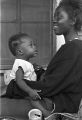 Young woman holding a baby while sitting on the porch of a house in Little Korea, a neighborhood in Birmingham, Alabama.