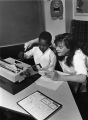 A female student helps a young boy at a typewriter in the Hartman Education Clinic, 1988