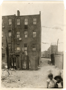 Two children standing near 19-25 Hubert Street, Roxbury, Mass., June 1, 1923