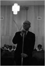 Rev. Jesse Douglas standing at a microphone at Holt Street Baptist Church in Montgomery, Alabama.