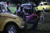 Group of men gathered around Volkswagen automobiles