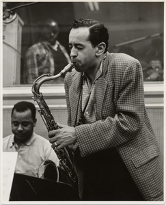 [Jimmy Hamilton, Paul Gonsalves (foreground, playing saxophone), Bobby Boyd, valet and bandboy (background in recording booth), black-and-white photoprint,] 1956