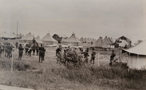 Thumbnail for View of a black army band playing music amongst rows of tents in a German prisoners camp behind a barbed wire fence