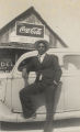 African American man standing in front of a car parked in front of a store.