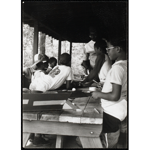 A group of youth stand around a craft table with a supervisor