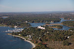 An October 2017 aerial view of New Castle, New Hampshire, with the historic seaport of Portsmouth, the largest city along the shortest coastline (18 miles) of any U.S. state, in the distance. The large white building with a red roof is the 1874 Wentworth-by-the-Sea Hotel, a historic grand resort hotel in New Castle. Now managed by Marriott, it is one of a handful of the state's surviving Gilded Age grand hotels, and the last located on the seacoast