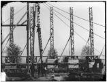 Workmen erect latticed cores for construction of the Varied Industries building