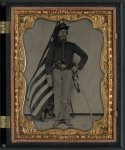 [Unidentified soldier in Union cavalry uniform with Colt Dragoon revolver and sword in front of American flag]